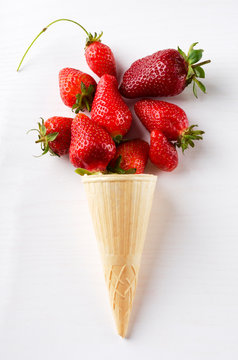 Vertical image.Waffle cone and fresh ripe strawberries on the shite surface.Summer ice cream with natural fruits