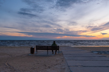 Fototapeta na wymiar A man sits on a bench near the sea