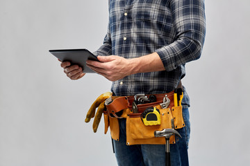 repair, construction and building - male worker or builder with tablet pc computer working tools on belt over grey background