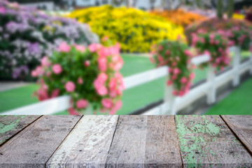 Empty vintage wooden table in font of blurry colorful flower blooming in the garden and flare abstract background with copy space. Product display montage