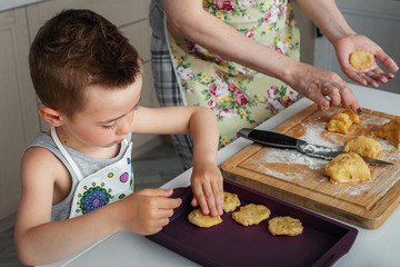 Obraz na płótnie Canvas Cute little boy with mom prepares cookies