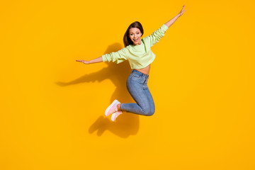 Fototapeta na wymiar Full length photo of careless energetic girl jump hold hand enjoy fly like plane wear good look clothes sneakers isolated over bright color background