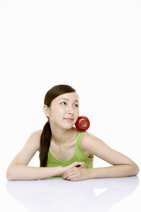 Woman balancing a red apple between her face and shoulder.