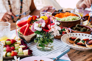 Close up of table full of food and flower decoration - colorful decorations and vegetarian lunch concept for group of people together eating and celebrating traditions