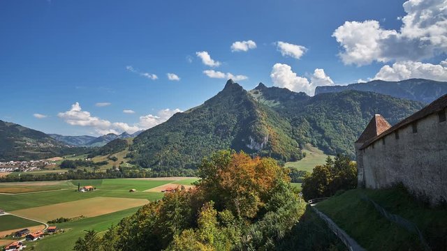 Time lapse view of a castle wall overlooking a beautiful valley surrounded by green countryside and trees with mountains in the background in the town of Chur, Switzerland