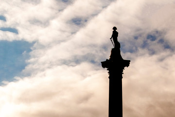 Nelson's column silhouette in Trafalgar Square, London against a cloudy sky at dusk