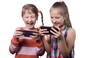Two cute little girls posing with mobile phones.