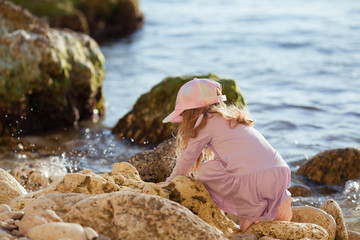 Happy pretty girl walks along the sea coast against the background of the sea, from behind a beautiful landscape