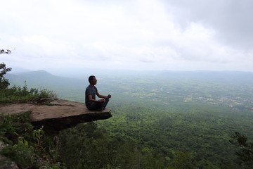 Man sitting at the edge of a cliff Sai Thong National Park in Chaiyaphum, Thailand.