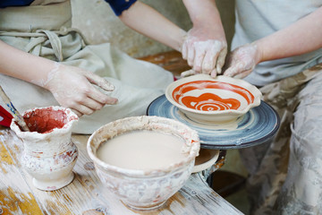 Obraz na płótnie Canvas a master potter teaches a student to work on a pottery wheel.