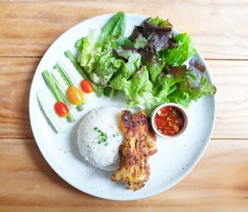 Top view shot of grilled chicken fillet served with steamed rice, salads and spicy hot sauce.