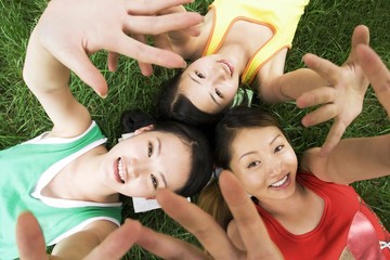 Three young women lying on the field posing for the camera