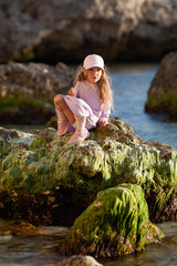 Happy pretty girl walks along the sea coast against the background of the sea, from behind a beautiful landscape
