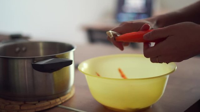 Millennial young woman cooking food, peeling carrot at home kitchen. Circular economy, real food, organic waste