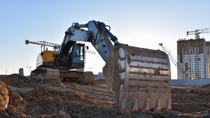 Excavator working at construction site on road work. Backhoe digs ground for the foundation and for...