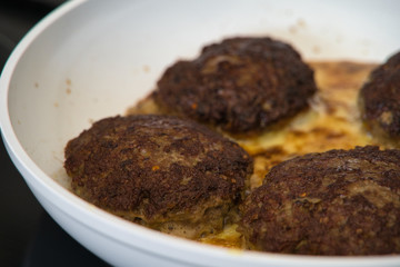 Frikadellen Gemüse Fleisch Paddys mit Kurkuma beim Anbraten in weißer Teflonpfanne mit Kokosöl, Produktbild