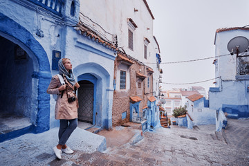 Traveling by Morocco. Young woman walking in medina of blue city Chefchaouen.