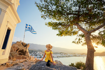 Vacation in Greece. Young traveling woman enjoying sunset on sea on Poros tower view point.