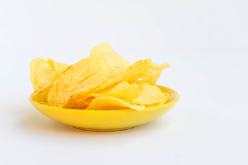 Potato chips in a yellow dish isolated on white. Non healthy food concept in a white background.
