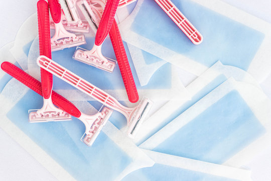 Pink disposable razor blades and hair removal strips isolated on white. Beauty, hair removal and woman care concept. Plastic waste.