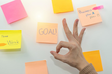 Goal. business woman showing OK hand with colored sheets sticky note paper on white board background in office, business meeting, brainstorming, creative, digital online marketing, financial concept