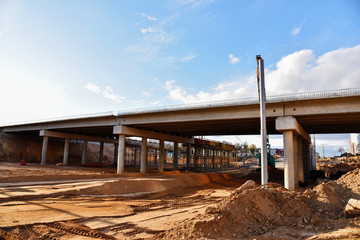 Roundabout and traffic bridge construction. Construction highway ramps and bridgeworks. Crane for formwork on bridge project works. Road work on traffic highway, road intersection junction and freeway
