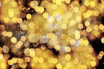 Blurred view of gold lights on black background, bokeh effect