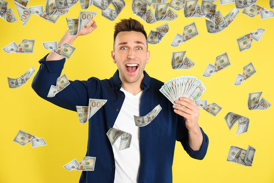 Man with American dollars under money rain on yellow background