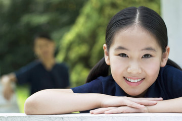 Girl smiling at the camera with her mother standing in the background