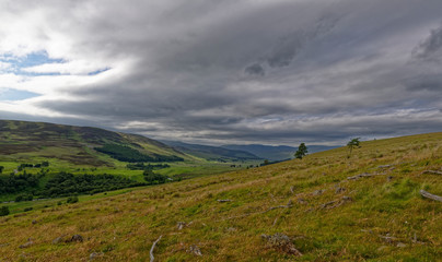 Fototapeta na wymiar Looking down the Valley of Glen Clova from the hillside between Glen Moy at a site of Old Tree Felling operations, with threatening storm clouds above.