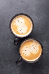 Two cups with coffee on dark stone background. Top view. Copy space