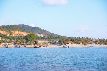 Koh Samui's beach filled with houses, hotels, boats and tourists. A view from the water.