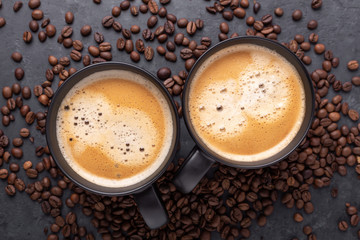 Cups with coffee and coffee beans on dark stone background. Top view. Copy space