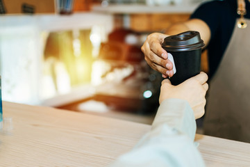 man barista serving hot coffee cup to friendly female customer