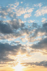 sun sets behind the clouds in the blue evening sky