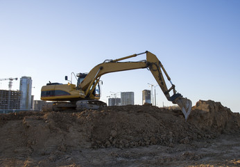 Fototapeta na wymiar Excavator working at construction site. Backhoe during earthworks. Digging ground for the foundation and for laying sewer pipes district heating. Earth-moving heavy equipment
