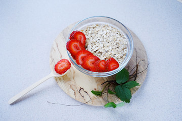 
glass bowl with fresh strawberries and oatmeal on a light background
