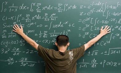 Young man sticking to blackboard full of formulas