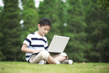 Boy using laptop in the park