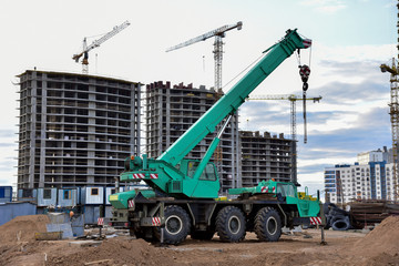 Mobile auto crane at construction site. Work of truck crane on project works. Tower cranes and builders in action