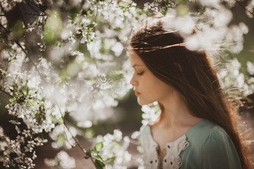 beautiful young girl with long flowing hair in a blooming cherry blossoms garden