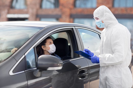 Medicine, Quarantine And Pandemic Concept - Doctor Or Healthcare Worker In Protective Gear Or Hazmat Suit, Medical Mask, Gloves And Goggles With Clipboard And Woman In Car Waiting For Coronavirus Test