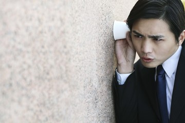 Businessman eavesdropping by listening through a cup