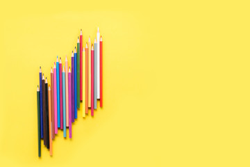 Colorful pencils on the yellow background outer space for text place
