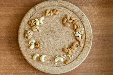 Almonds cashews walnuts are scattered on a wooden cork background top view on a round stand for texts notes and menus