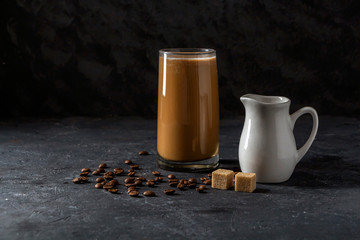 Ice coffee frappe in tall glass. Cool summer drink on a dark background in low key. Close up, copy space for text