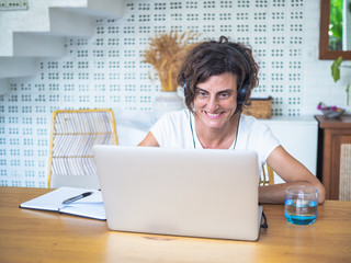 
happy smiling remote woman talking and flirting with headset, laptop, notebook, pen and glass in...