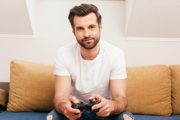 KYIV, UKRAINE - APRIL 14, 2020: Handsome man playing video game on couch