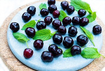 cherry with Melissa leaves on a plate made of stone and cork