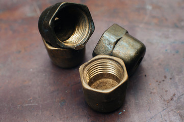 Brass scrap metal: taps, tees, plugs and various plumbing parts, spare parts. Against the background of a copper sheet. Close-up.